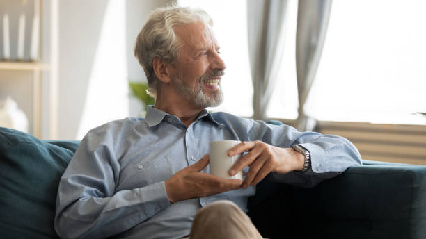 istock Happy elderly man resting on sofa with cup of tea. 1226093634