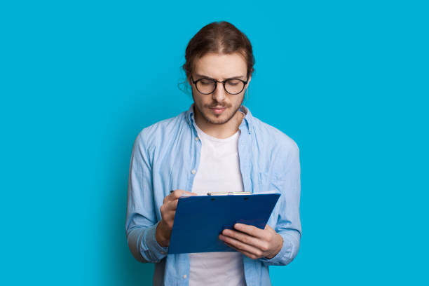 istock Young caucasian entrepreneur with long hair and beard writing something on a blue wall 1226094945