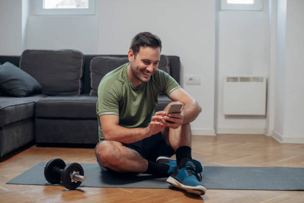 istock Home Workouts: a Man Picking Exercises on his Fitness Mobile App 1226096009