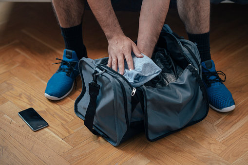 Anonymous man in sportswear getting ready to go running: packing his sports bag.