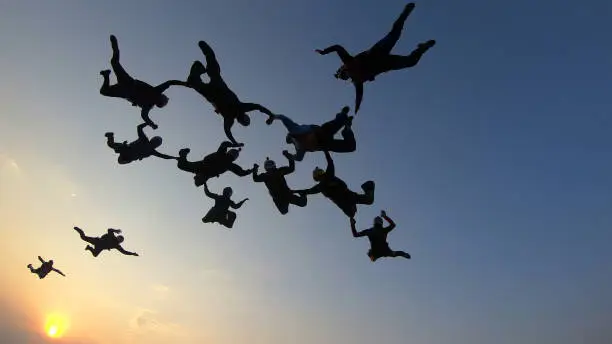 Photo of Silhouette of a group of skydivers jumping at the end of the day.