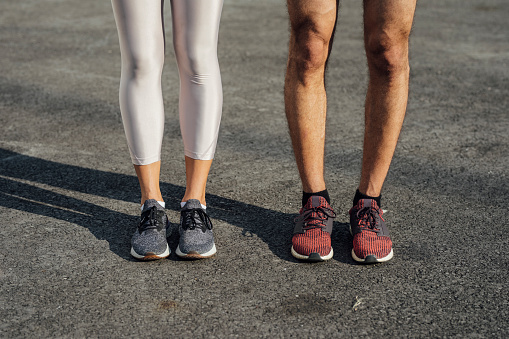 Unrecognizable man and woman in sportswear standing outdoors together.