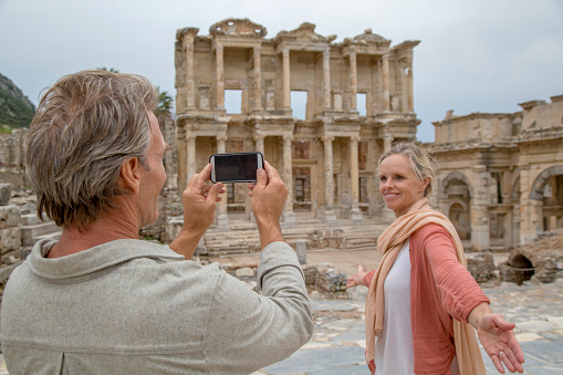 Man takes photo of woman in front of archaeological site