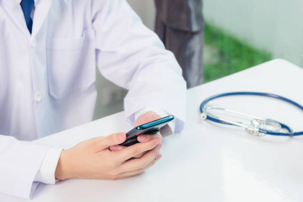 istock Asian doctor young handsome man smiling using working or holding with digital smart mobile phone at hospital desk office, Technology healthcare medical concept 1226103066