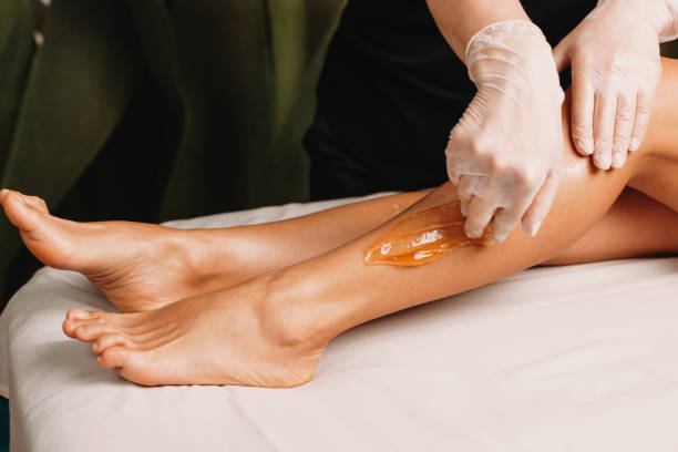 foto ravvicinata di una procedura di zuccheraggio eseguita al salone durante una sessione di protezione della pelle delle gambe - depilazione foto e immagini stock