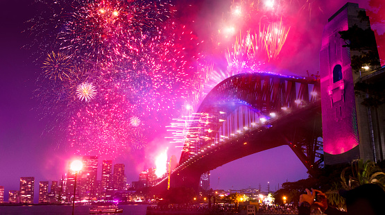 Sydney, Australia - January 1, 2020: Colorful Sydney New Year's Eve Fireworks over Sydney Harbour Birdge with reflections on water and fireworks on bridge.