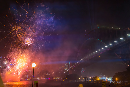 Sydney, Australia - January 1, 2020: Colorful Sydney New Year's Eve Fireworks over Sydney Harbour Birdge with reflections on water and fireworks on bridge.