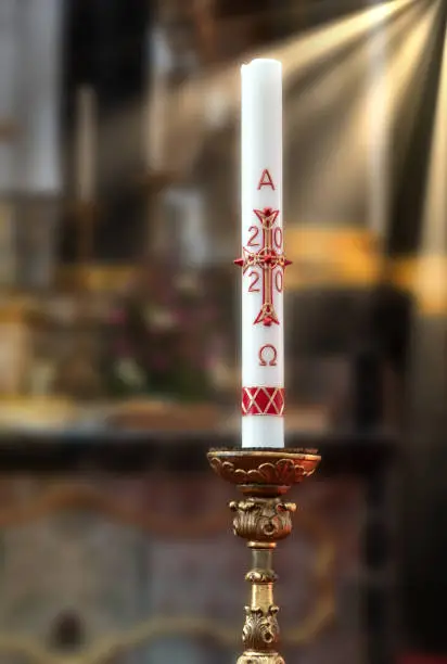 Paschal candle (Osterkerze) 2020 on the altar. Blurred background with sun rays