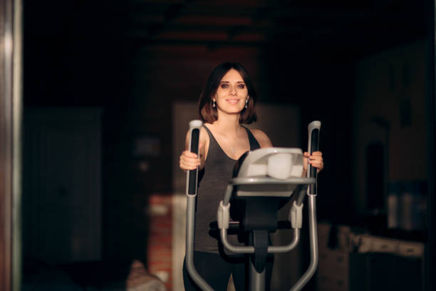 femme enceinte exerçant sur la machine elliptique à la maison - cross trainer photos et images de collection