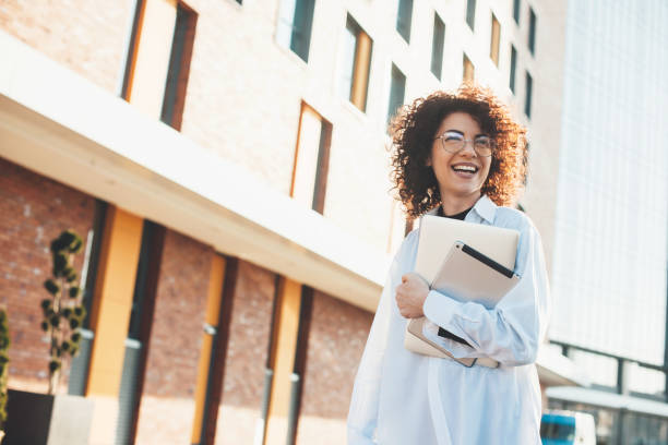 istock Caucasian lady with curly hair is posing outside with some modern gadgets while walking 1226112717