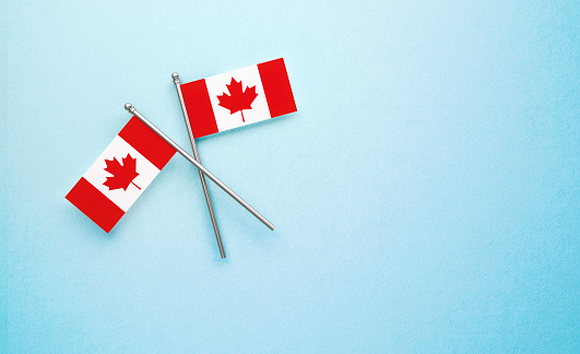 Tiny Canadian flag pair on light blue background. Horizontal composition with copy space. Directly above.