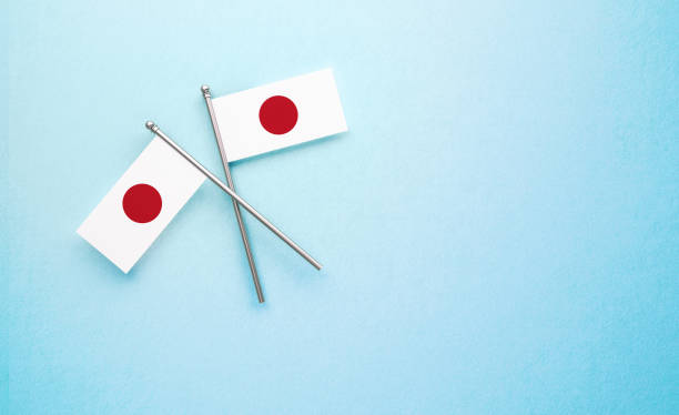 pequeño par de bandera japonesa sobre fondo azul claro - japan flag japanese flag white fotografías e imágenes de stock