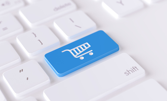 Shopping cart icon written on a blue button of a computer keyboard. Horizontal composition with selective focus and copy space. High angle view.  Online shopping concept.