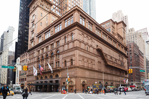 New York, New York, USA -  February 10, 2016: Carnegie Hall in Manhattan. Located on the corner of 57th St. and 7th Ave., Carnegie Hall is one of the most well known concert halls in the world. People and vehicles can be seen.