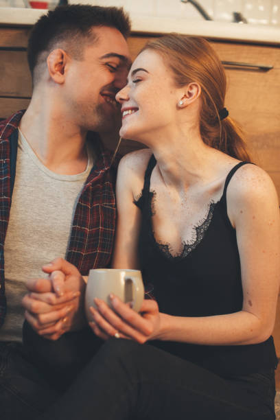 istock Caucasian man whispering something to his wife while having a coffee break in kitchen on the floor 1226122098