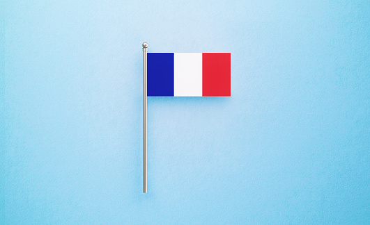 Tiny French flag on light blue background. Horizontal composition with copy space. Directly above.