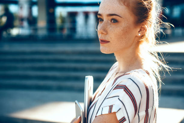 istock Wonderful ginger lady with freckles is looking away thinking about something while posing with some modern gadgets 1226122318