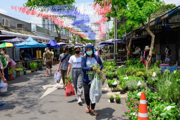 multidão de pessoas usando máscara cirúrgica e caminhando no chatuchak plant market - head ware - fotografias e filmes do acervo