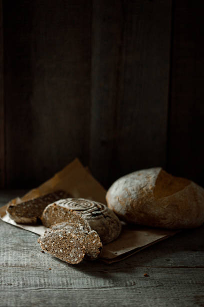 Healthy rye whole grain round bread on brown craft paper on black wooden table