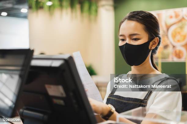 Asian Staff Restaurant Waitress Wear Protective Face Mask Working In The Restaurant With Social Distancing To Protect Infection From Coronavirus Covid19 Stock Photo - Download Image Now