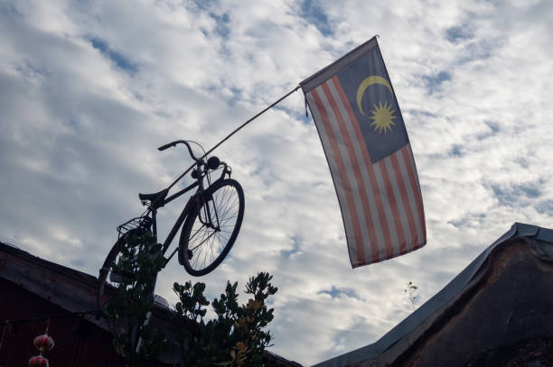 Malaysia flag hang on bicycle waving in cloudy day.