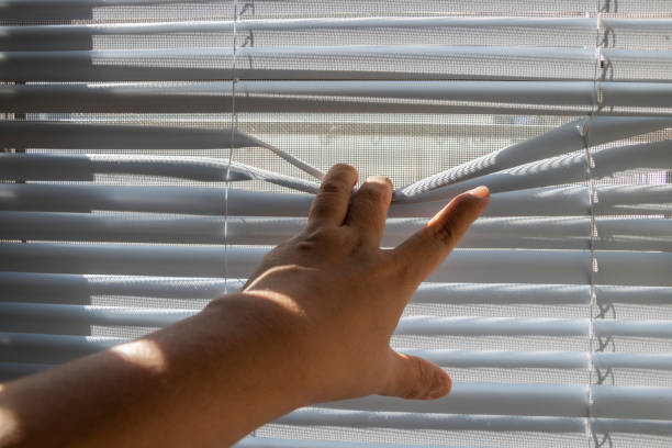 istock The fingers stretched the window blinds looking outside. 1226135713