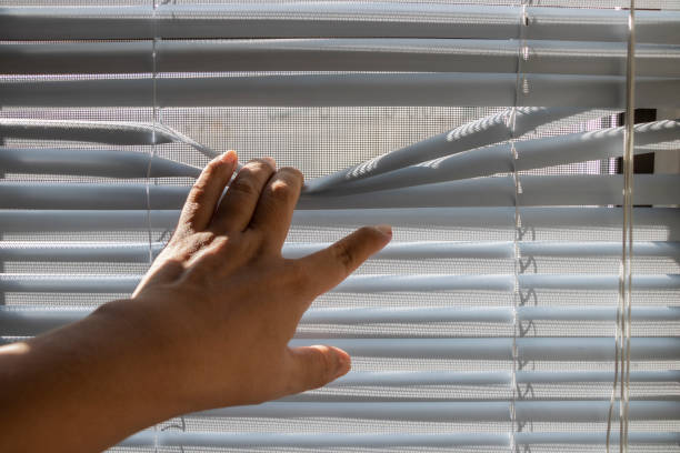 istock The fingers stretched the window blinds looking outside. 1226135715