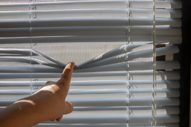 istock The fingers stretched the window blinds looking outside. 1226135719