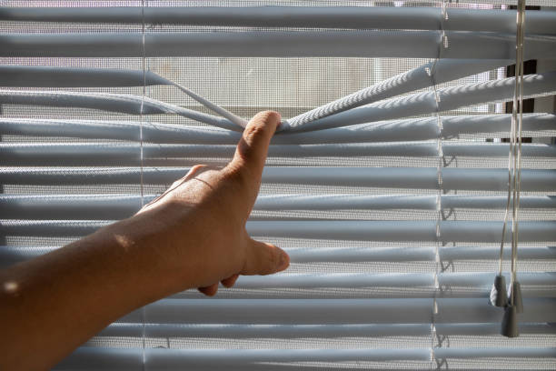 istock The fingers stretched the window blinds looking outside. 1226135721