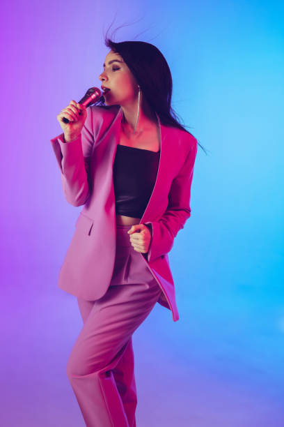 istock Caucasian female singer portrait isolated on gradient studio background in neon light 1226150071