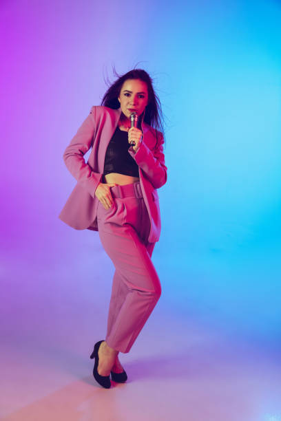 istock Caucasian female singer portrait isolated on gradient studio background in neon light 1226150082