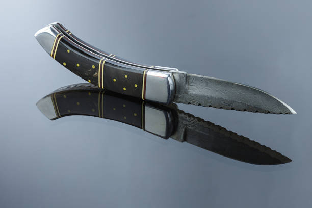 istock folding pocket knife on a mirrored surface, blade made of multi-layer Damascus steel, handle made of Damascus steel, bone pads, aluminum spacers 1226152133