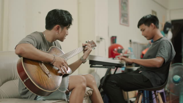 Asian man playing his guitar on the house with friends stock video