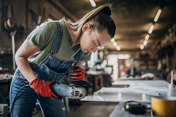 Wanita muda bekerja dengan penggiling sudut di bengkel