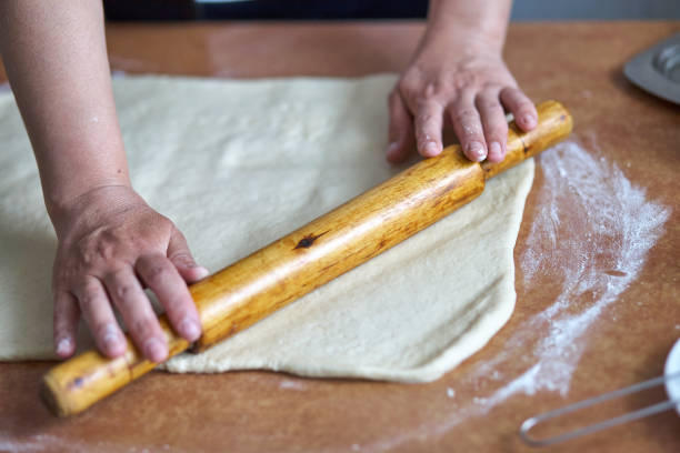istock Women's hands roll the dough on the kitchen table. Women's hands with rolling pin 1226160384