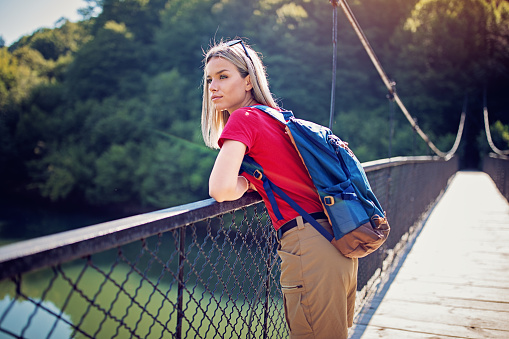 Beautiful hiker woman is looking the view on a rope bridge