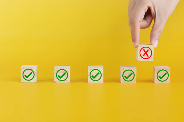 istock fingers pick wooden cube with X mark raised up to create space between each other. social distance or physical distancing for the new normal concept, avoid spreading germ during COVID-19 outbreak 1226164607