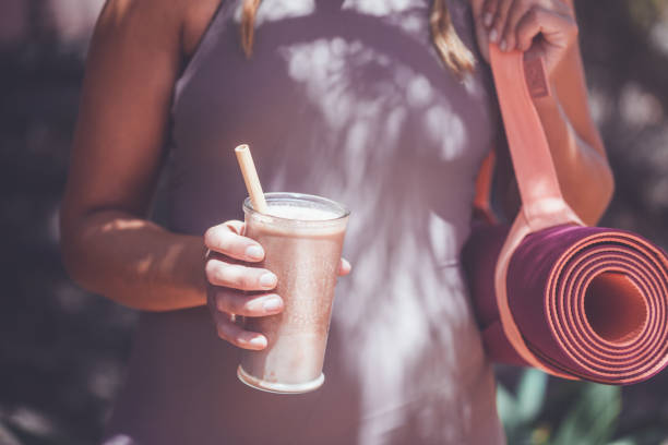 Woman with smoothie and yoga mat - fotografia de stock