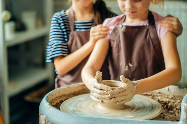 istock pottery workshop - girls sculpts from clay on pottery wheel 1226172051
