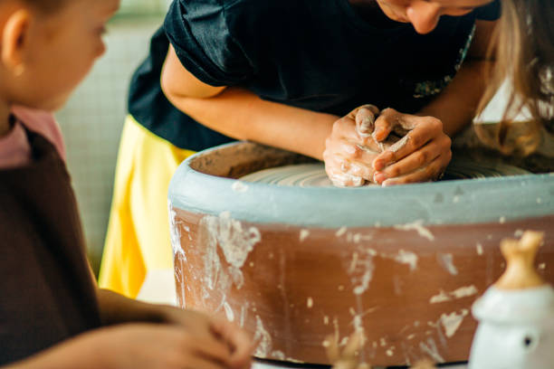 istock Hands of young potter, close up hands made cup on pottery wheel 1226176192