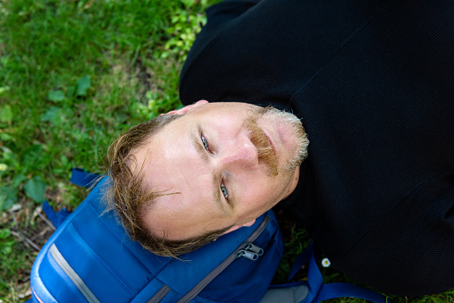 Portrait of a handsome man on the grass. Happy man relaxing outdoors lying on the grass