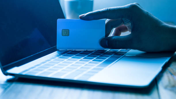 The concept of credit card theft. Hackers with credit cards on laptops use these data for unauthorized shopping. Unauthorized payments from credit card owners. In the hacker's secret office stock photo