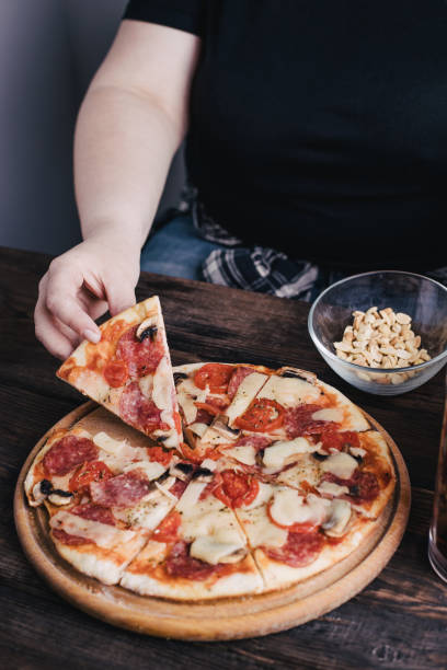 istock Overweight woman eating pizza 1226186587