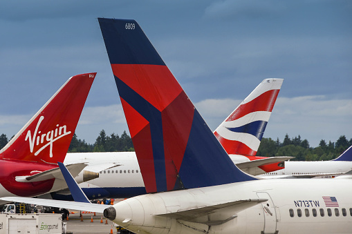 Seattle, WA, USA - June 2018: Close up of tail fins of aircraft operated by British Airways, Virgin Atlantic and Delta Airlines at Seattle Tacoma airport.