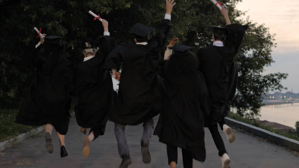 cinco jóvenes graduados saltan mientras caminan - men jumping mid air air pump fotografías e imágenes de stock