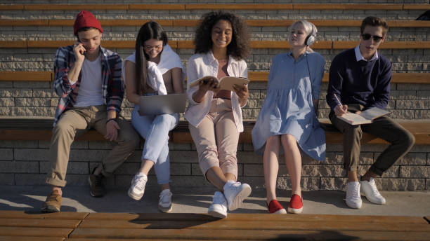 istock Group of young people sitting together doing different things 1226201589