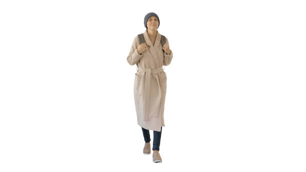 istock Young woman wearing coat and backpack walking on white background 1226205285