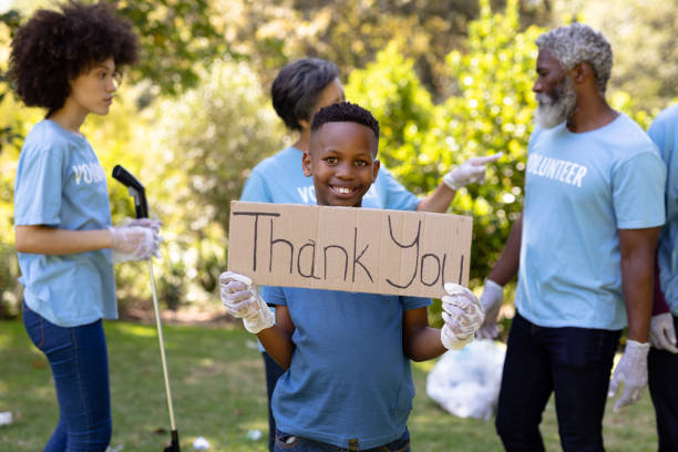 istock Multi-generation people collecting garbage with a boy holding a sign written Thank You 1226206609
