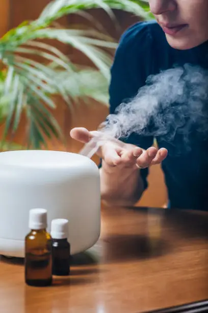 Photo of Woman Enjoying Aroma Therapy Steam Scent from Home Essential Oil Diffuser or Air Humidifier