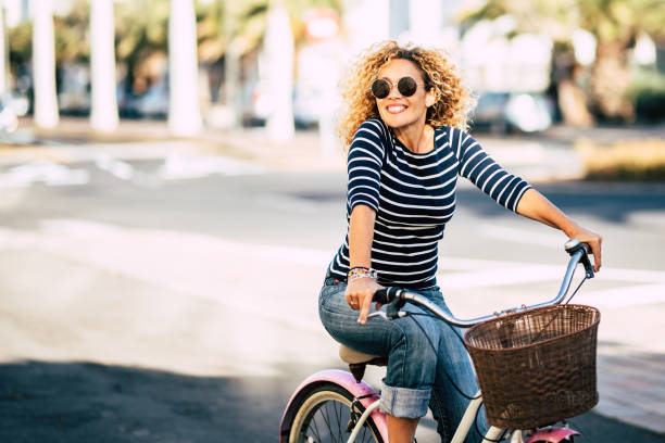 linda e alegre jovem adulta desfruta de passeio de bicicleta em ensolarado urbano atividade de lazer ao ar livre na cidade - retrato de pessoas felizes - mulher da moda fora se divertindo - bicycle ride - fotografias e filmes do acervo